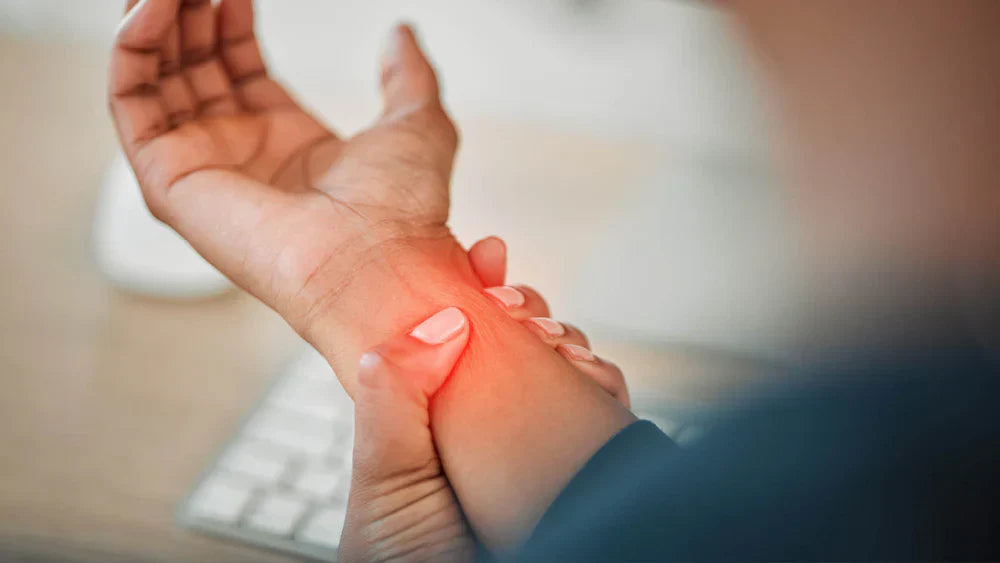 Nahaufnahme einer Person, die sich schmerzhaft das Handgelenk hält; roter Lichtpunkt zeigt Entzündung oder Nervenschmerz – Hinweis auf Karpaltunnelsyndrom o. Ä